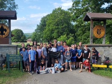 A group of scouts posing at Camp Gorton entrance under sunny skies.