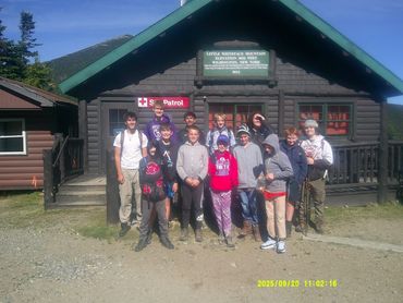 Group of young hikers posing in front of a mountain patrol cabin.