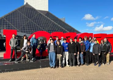 Group of teenagers posing in front of a large red "LOVE" sign outdoors.