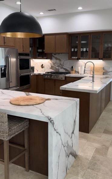 Modern kitchen with marble countertops and wooden cabinets.