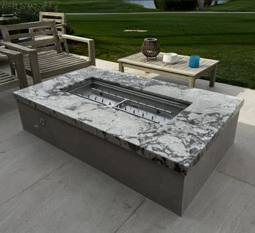 Modern outdoor fire pit with marble top and wooden seating area.