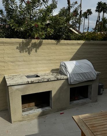 Outdoor kitchen setup with grill covered and storage compartments.