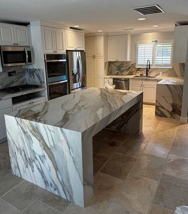Modern kitchen with marble countertops and beige tiled floor.
