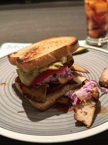 Grilled chicken sandwich with coleslaw and tomato on toasted bread.