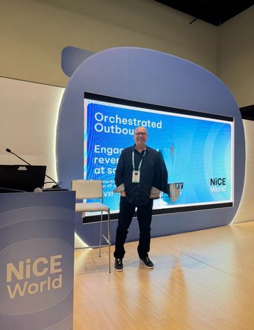Man standing in front of a NiCE World conference display.