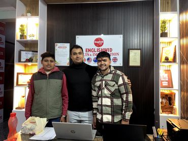 Three men posing inside an English language and immigration center.
