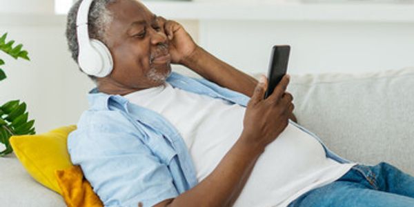 Man relaxing with headphones and smartphone on couch.