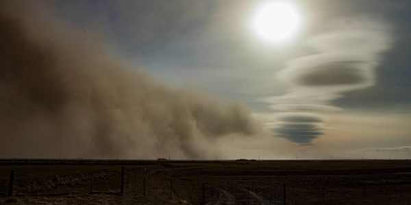 Sunlit sky over a dusty landscape with intriguing cloud formations.