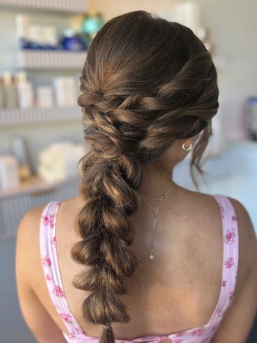 Intricate twisted and braided hairstyle on long brown hair.