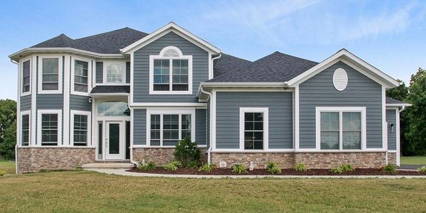 large grey home with white trim and stone foundation with flat lawn