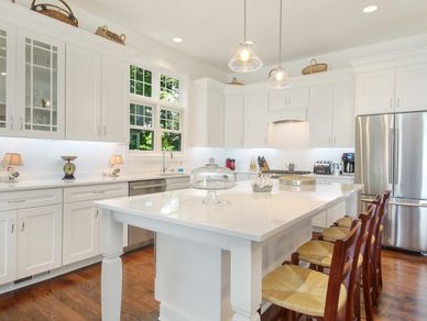 white kitchen with island and hanging lights with large fridge