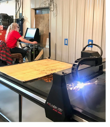 Person operating a CNC plasma cutting machine in a workshop.