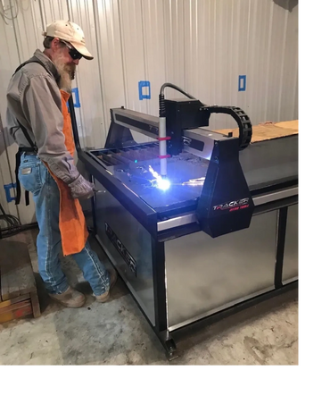 Man operating a plasma cutting machine in a workshop.