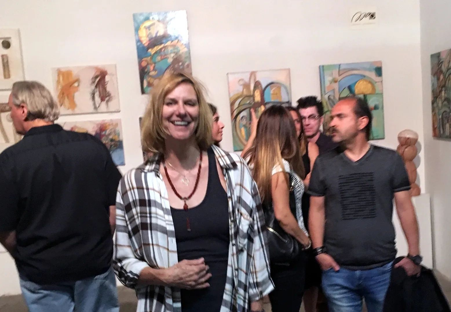 People enjoying an art gallery with colorful abstract paintings on the walls.