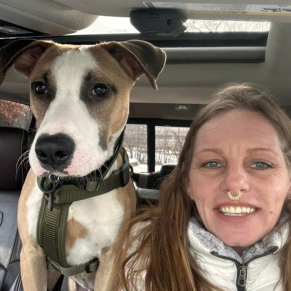 Woman smiling with her dog inside a car.
