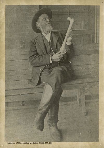 A.T. Still holding up a femur bone.