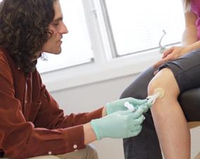 Dr. Leins giving an injection in a patient's knee.