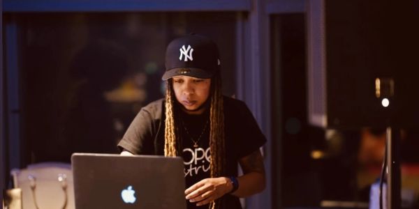 Person focused on a laptop, wearing a NY Yankees cap.