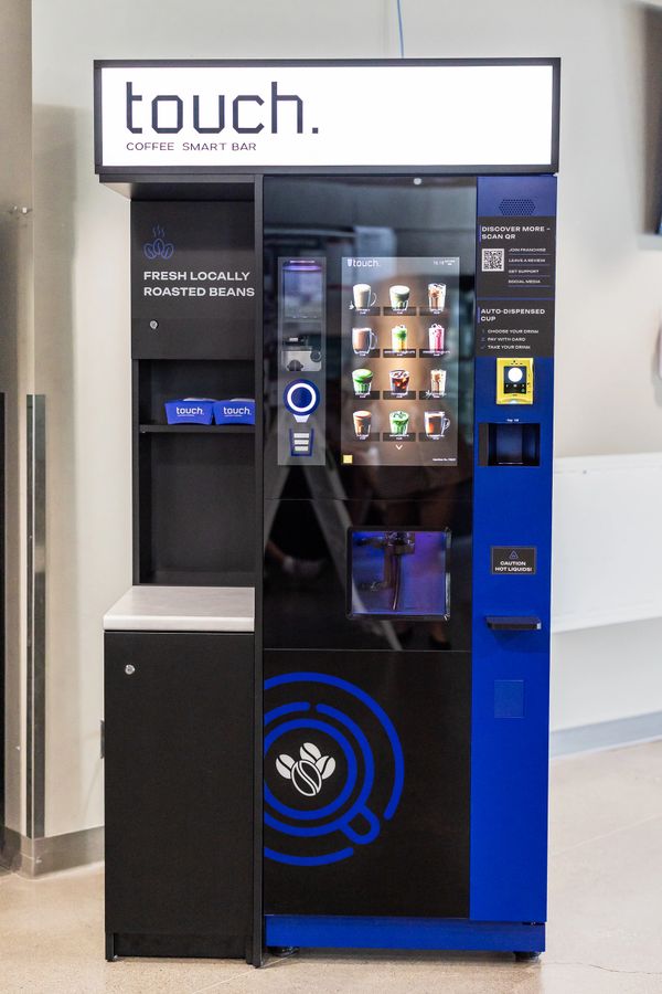 A sleek, modern coffee vending machine with touch screen options and fresh locally roasted beans.