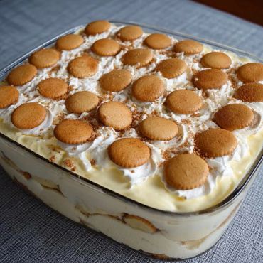 A glass dish filled with layered banana pudding topped with vanilla wafers.