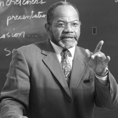 Teacher explaining a lesson in front of a blackboard.