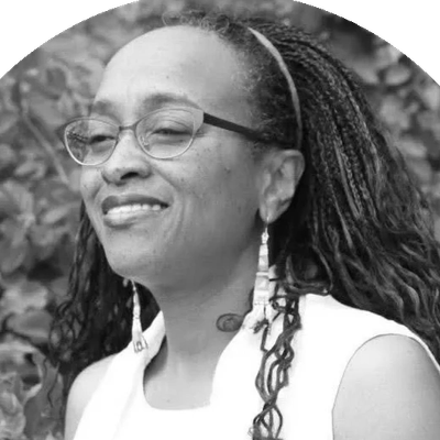 Woman with glasses smiling outdoors.