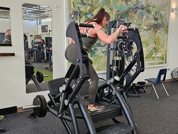 Woman working out on a leg press machine in a gym.