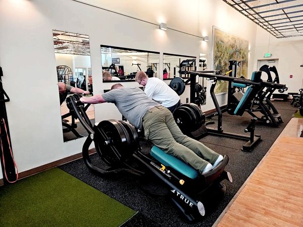 Two members, one using the total body press while the other is grabbing weights.
