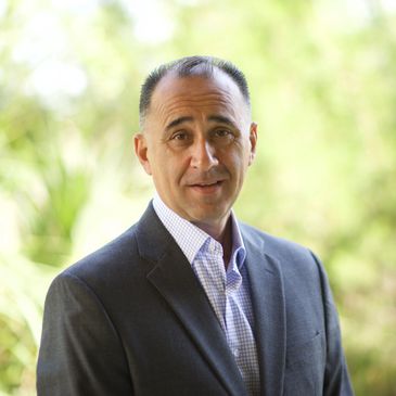 Professional man in business attire outdoors with a serene background.