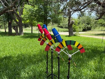Colorful wind spinners with red and blue cups in a green grassy yard.