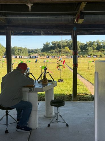 Man aiming a rifle at a shooting range with targets in the distance.
