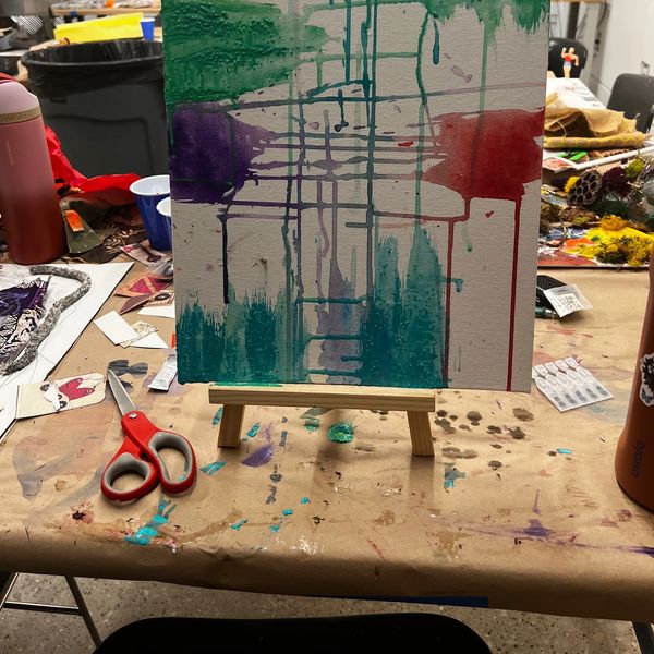 Abstract painting with dripping colors on an easel.