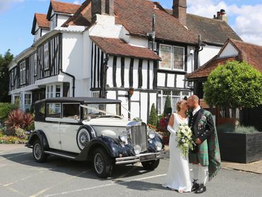 groom in kilt with bride and wedding car outside Marygreen manor hotel