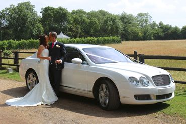 bride and groom leaning on a Bentley wedding car