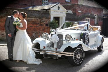 bride + groom next to open top vintage wedding car