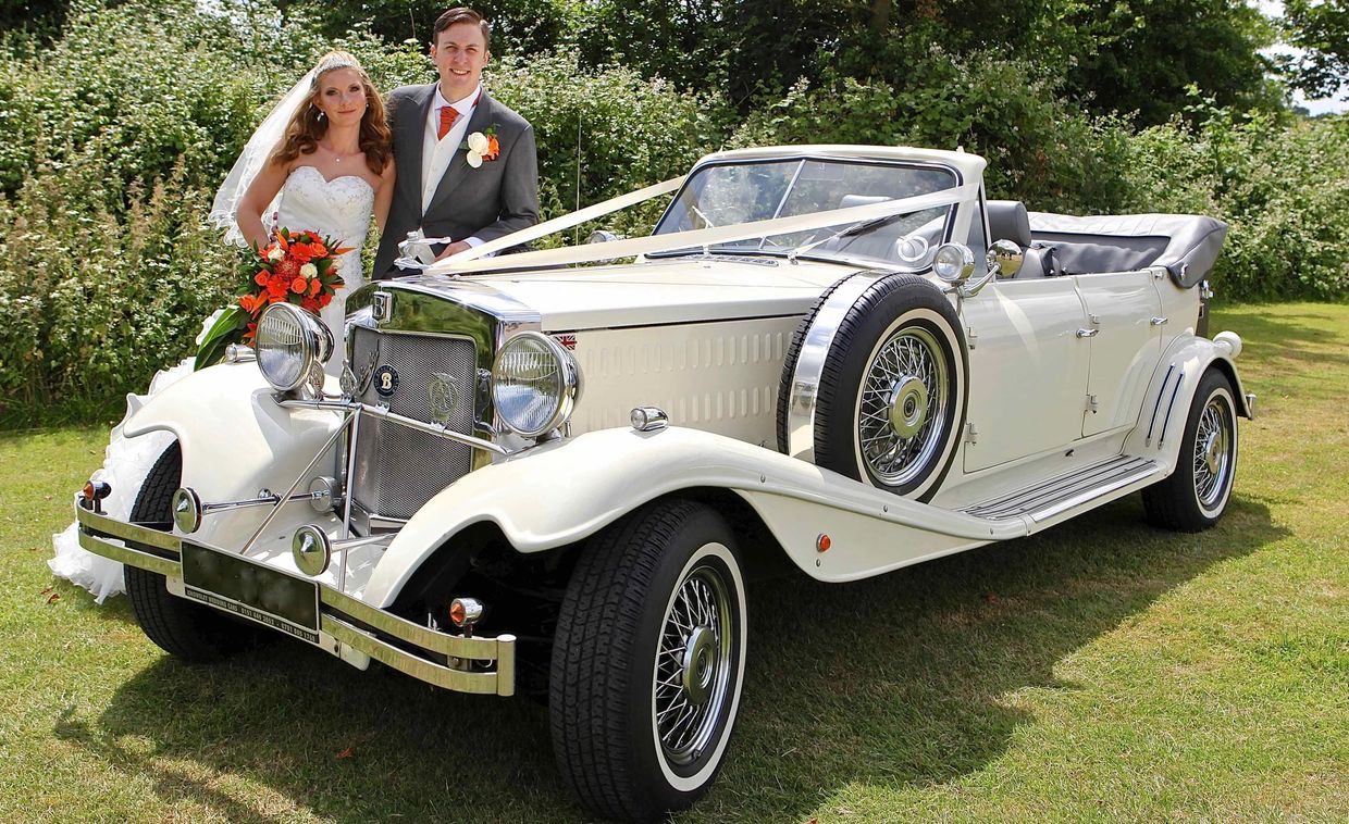 bride + groom standing next to Beauford wedding car