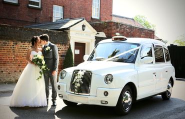 bride + groom kissing in front of white wedding taxi