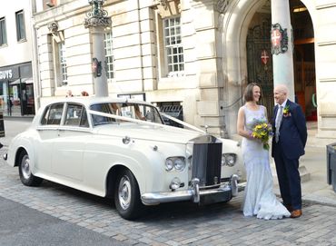 bride and father standing next to a Rolls Royce ar