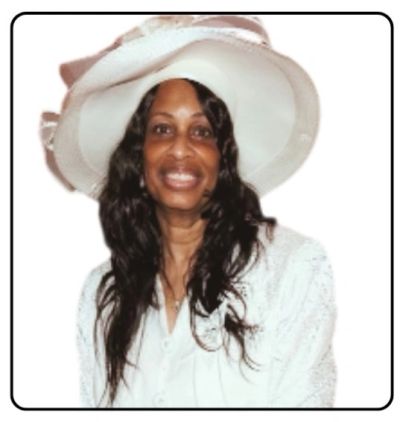 Woman smiling, wearing a white suit and elegant wide-brimmed hat.