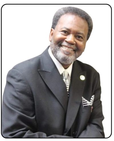 Smiling man in a dark suit with a striped tie.