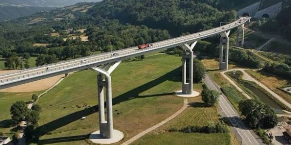 A long bridge over a green valley with vehicles.