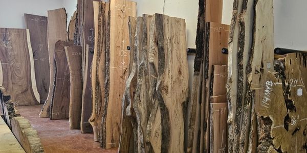 Rows of large, rough wooden slabs in a workshop.