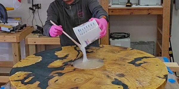 Person mixing resin on a wooden table.