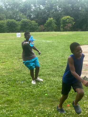 Kids playing with a water gun in a park.