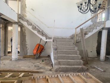 Concrete staircase under construction with an orange wheelbarrow.