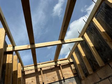 Wooden beams framing under a blue sky.