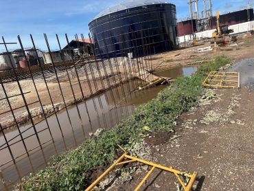 Construction site with metal framework and water puddles.