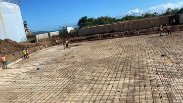 Construction workers prepare a large foundation with steel rebar.