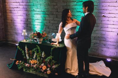 Bride and groom next to a table with flowers from Tiny Blooms Cottage. The wedding venue is Within