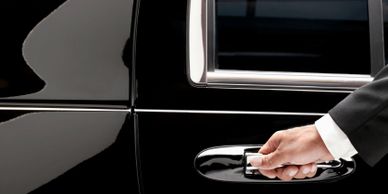Professional limousine driver grabbing onto door handle to open door 